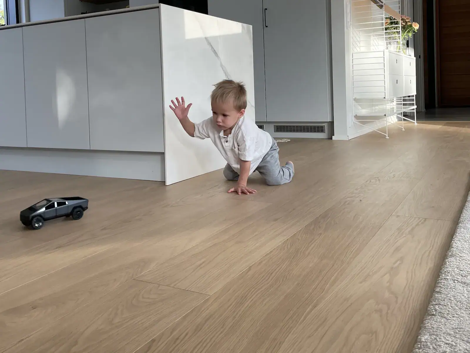 Lapsi leikkimässä turvallisesti lakatulla puulattialla.